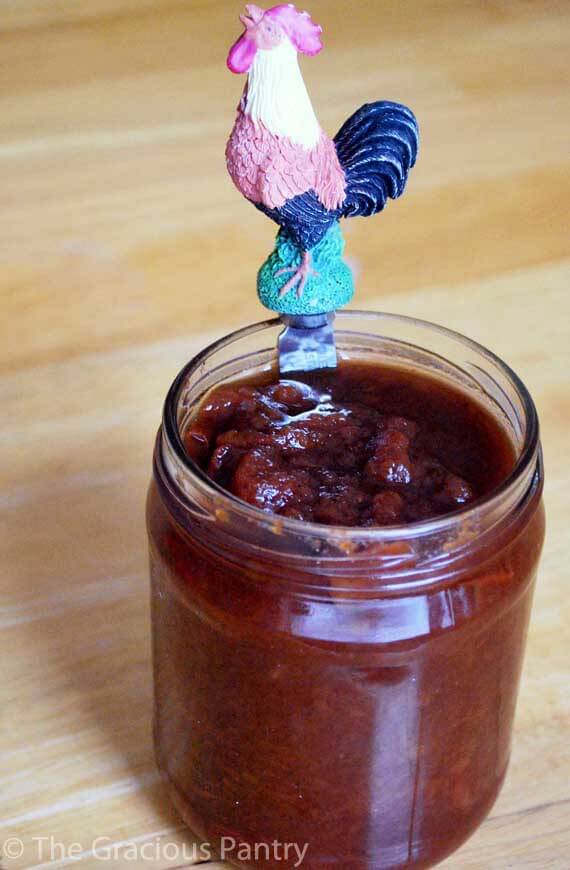 Homemade Apple Butter in a jar with the lid off. A butter knife sits in the jar and is ready to spread the apple butter over your morning toast!