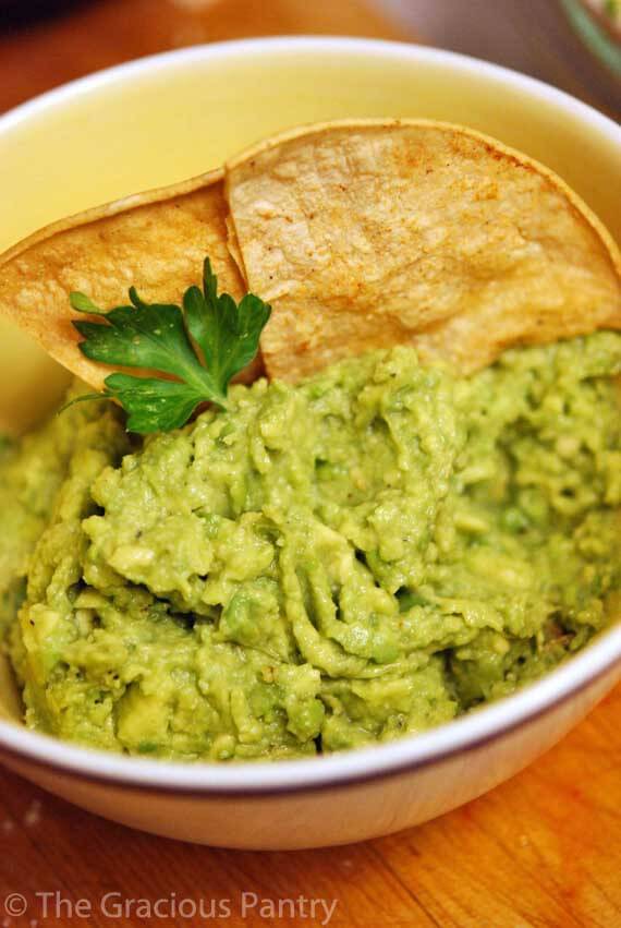 Clean Eating Chips And Guacamole in a bowl with two corn chips dipped in the guacamole.