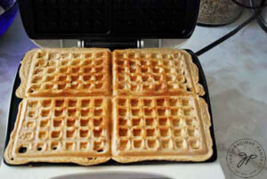 Waffles cooking on a waffle iron.