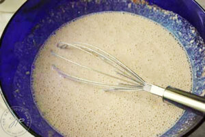 Whisked waffle batter in a blue mixing bowl.
