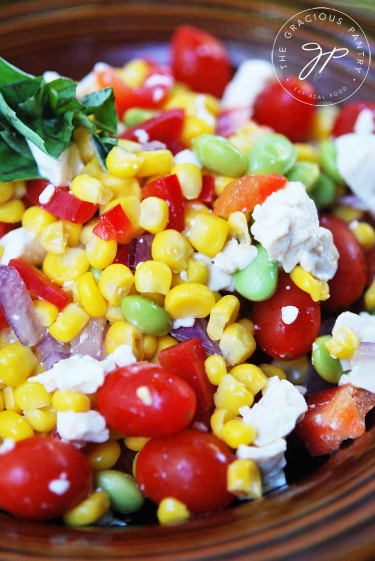 A close up shot of this Clean Eating Corn Salad showing all the bits of corn, feta and fresh basil as well as tomatoes.