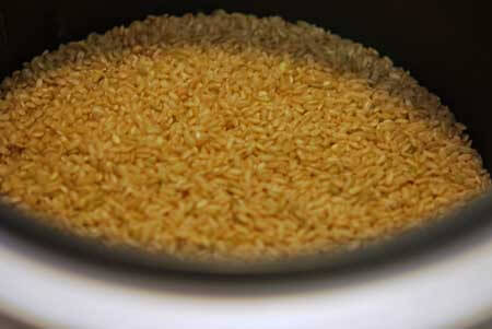 Rice in the rice cooker bowl, ready to be rinsed.