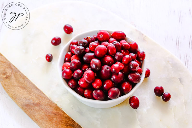 A white bowl filled with fresh cranberries.