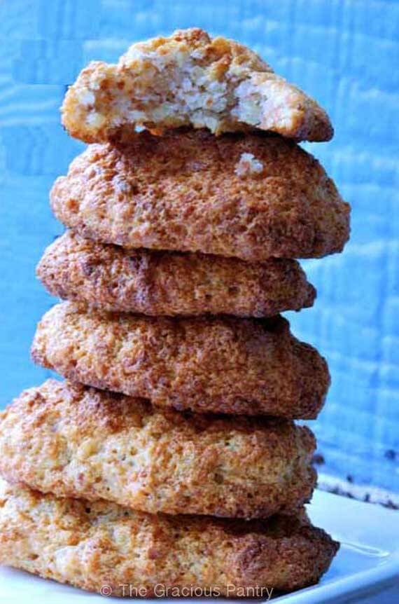 A stack of these Clean Eating Almond Honey Cookies sits on a white plate against a bright blue back drop. You can see the rough texture of the cookies. They look similar to oatmeal cookies without the raisins.