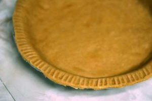 A finished pie crust in a pie pan.
