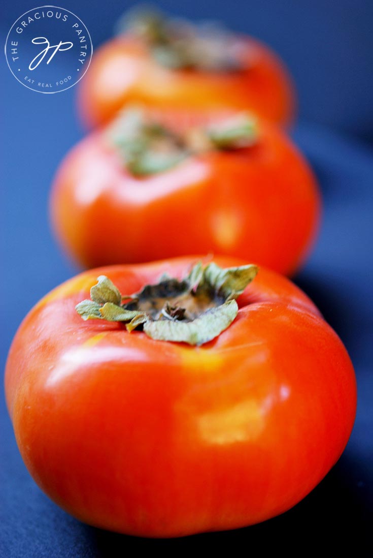 A row of persimmons sit waiting to be made into this Persimmon Butter Recipe.