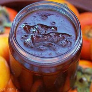 Persimmon Jam in an open jar, surrounded by persimmons.