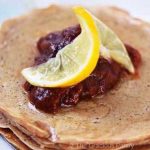 A closeup of a white plate holding as short stack of whole wheat pancakes.