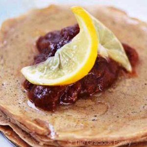 A closeup of a white plate holding as short stack of whole wheat pancakes.