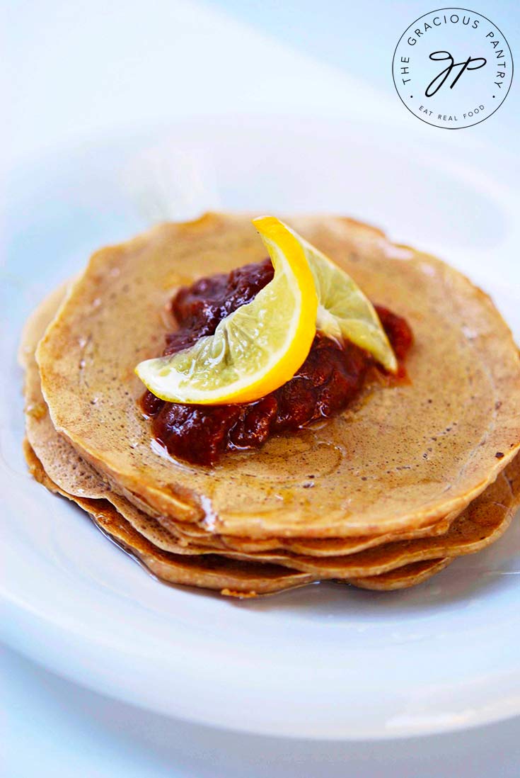 A delicious looking stack of Whole Wheat Pancakes topped with fruit compote and a lemon slice.