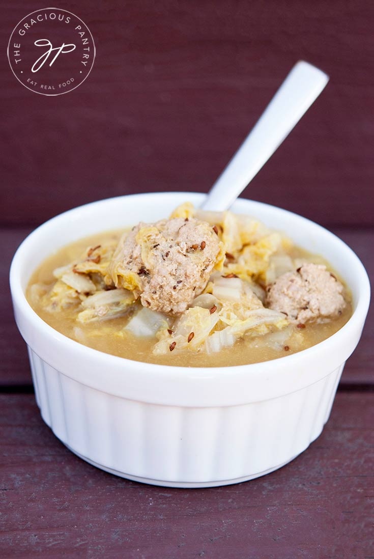 German cabbage soup served in a white bowl. A stainless steel spoon sits in the bowl.