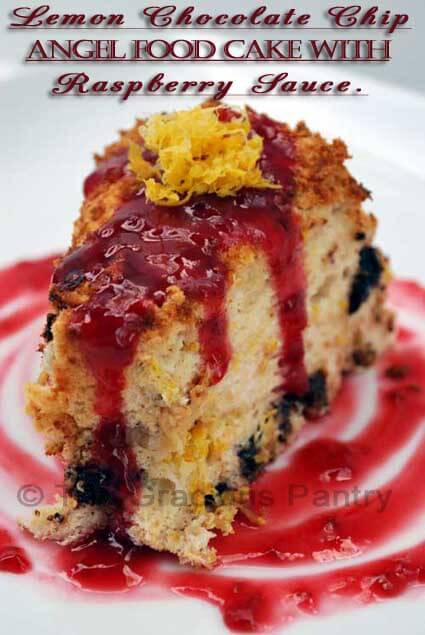 A slice of lemon chocolate chip angel food cake with raspberry sauce sits on a white plate. The sauce is swirled around the slice of cake.