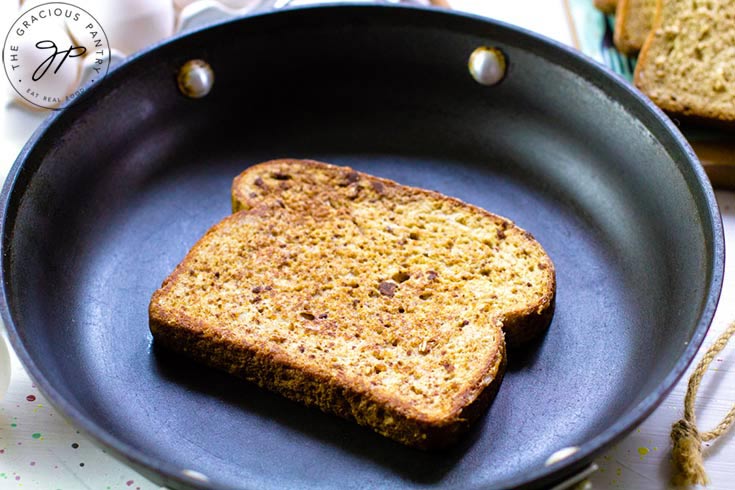 A single piece of french toast, cooking in a skillet.