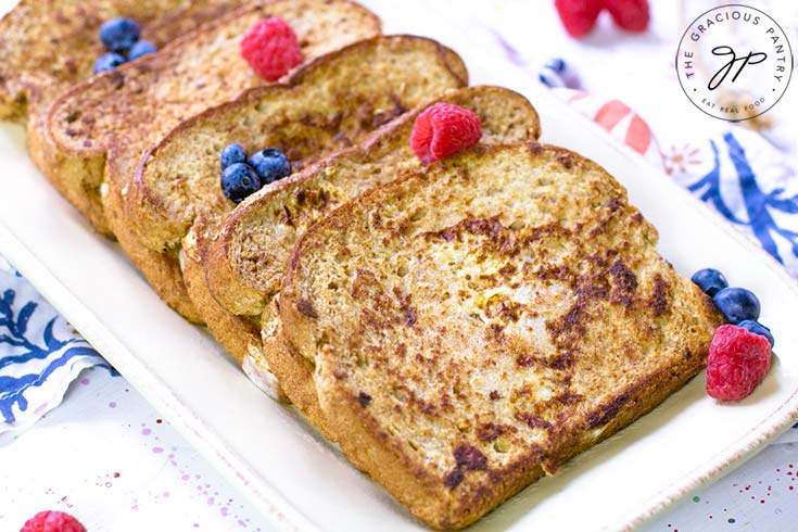 Healthy French Toast on a serving platter with fresh berries scattered over it.