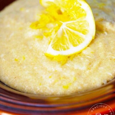 A bowl of Lemon Porridge sits garnished with a twisted lemon slice in the middle.