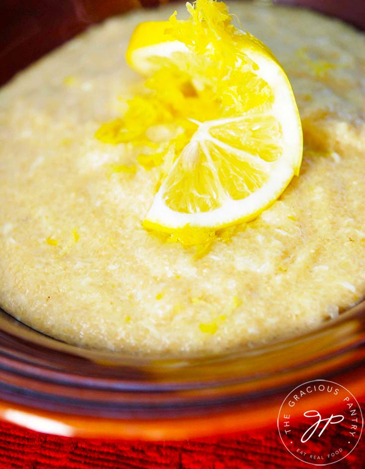 A bowl of Lemon Porridge sits garnished with a twisted lemon slice in the middle.