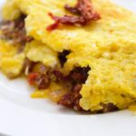 A delicious, Sun Dried Tomato Omelet sits served on a white plate, ready to eat.
