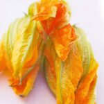 Three raw squash blossoms sit ready to be cooked with this Squash Blossoms Recipe.