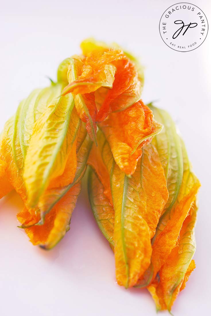 Three raw squash blossoms sit ready to be cooked with this Squash Blossoms Recipe.