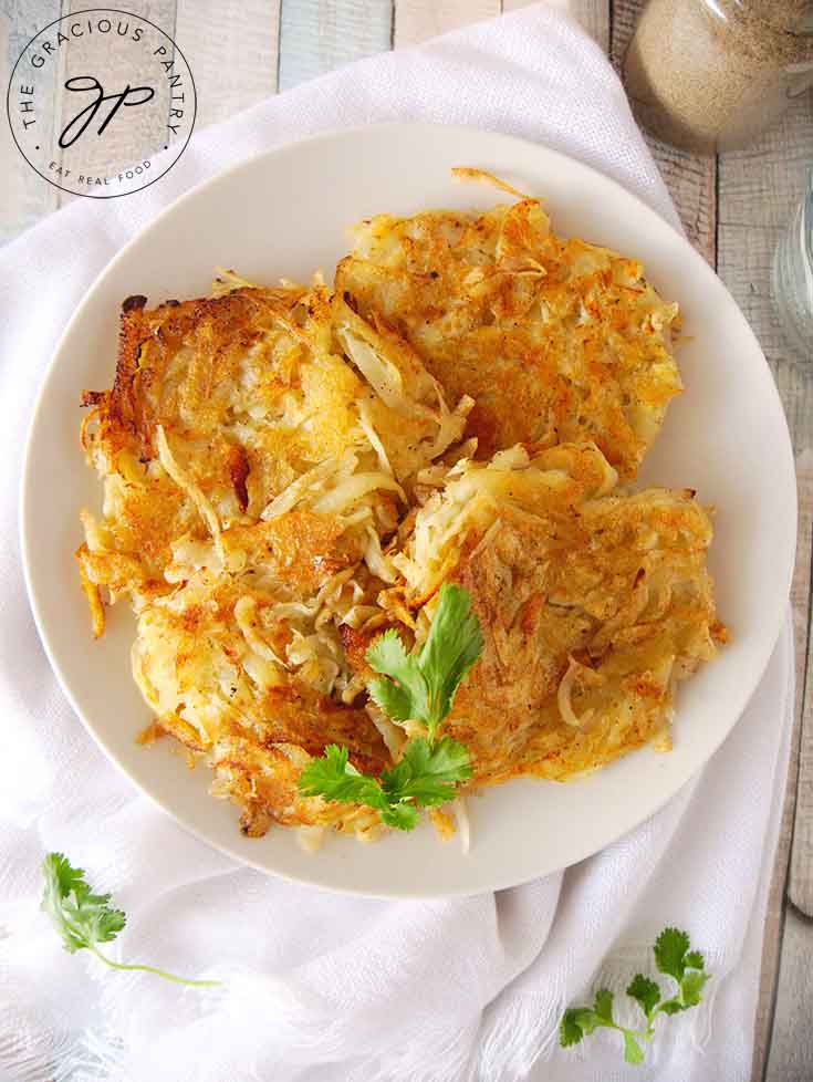This Homemade Hash Browns Recipe has been served on a white platter. A big stack of golden brown hash browns sits on a white plate, ready to eat.