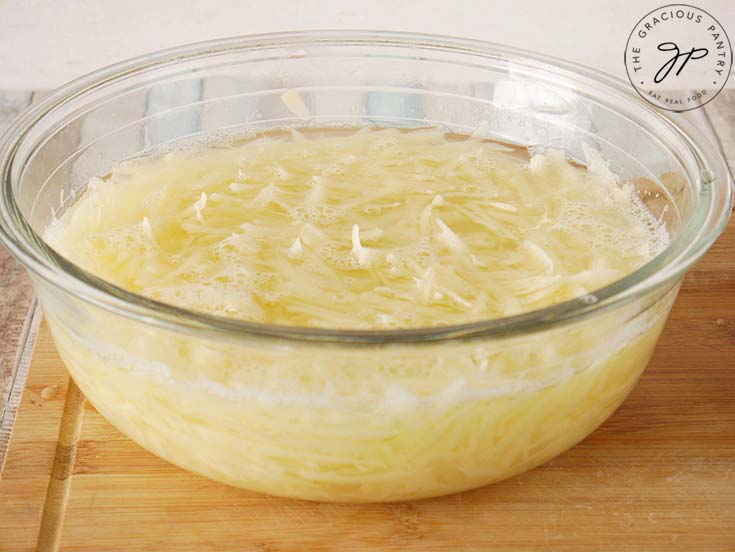 Place the grated potatoes in a bowl of water to help remove starch.