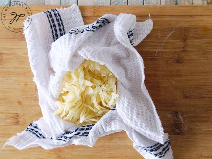 Wring out the potatoes in a tea towel or cheesecloth to remove as much water as possible.