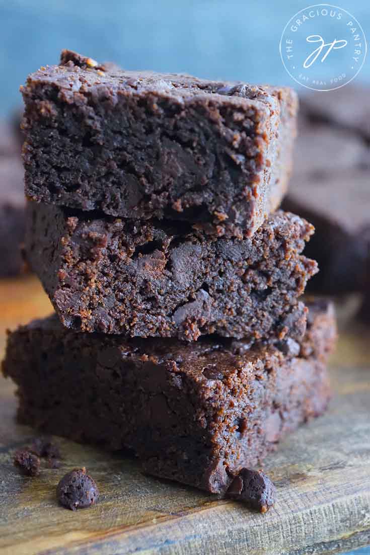 Healthy brownies stacked three high on a cutting board.