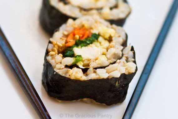 Chicken Sushi lined up on a white plate with black chopsticks.