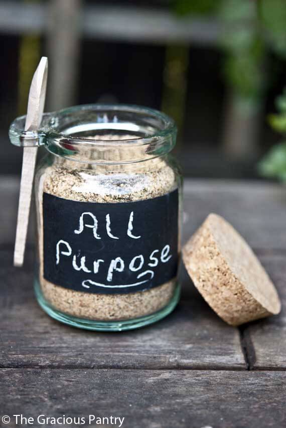 An open jar filled with all purpose seasoning. The lid rests on the side of the jar.