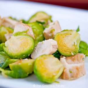 A white plate holds a serving of Chicken And Brussels Sprouts.