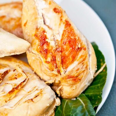 A plate of this Healthy Fried Chicken sits on a table, waiting to be served. The chicken breasts are sitting in a bed of greens.