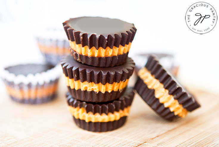 A head on view of a stack of 3 clean Eating Peanut Butter Cups stacked up with a few other single peanut butter cups scattered around the stack.