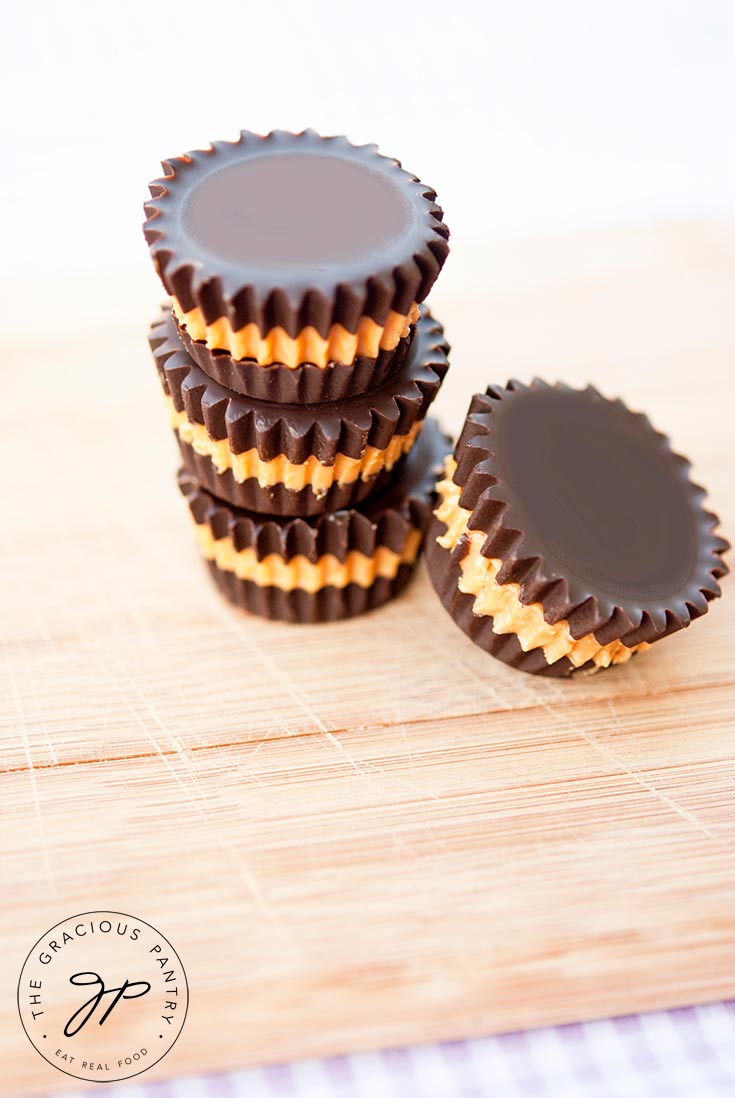 A stack of three clean Eating Peanut Butter Cups sits on a cutting board with a fourth leaning on it's side against the stack.