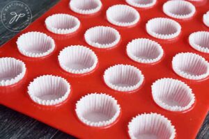 Lining muffin pan with muffin papers.