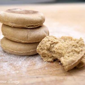 English Muffins piled up on a cutting board.