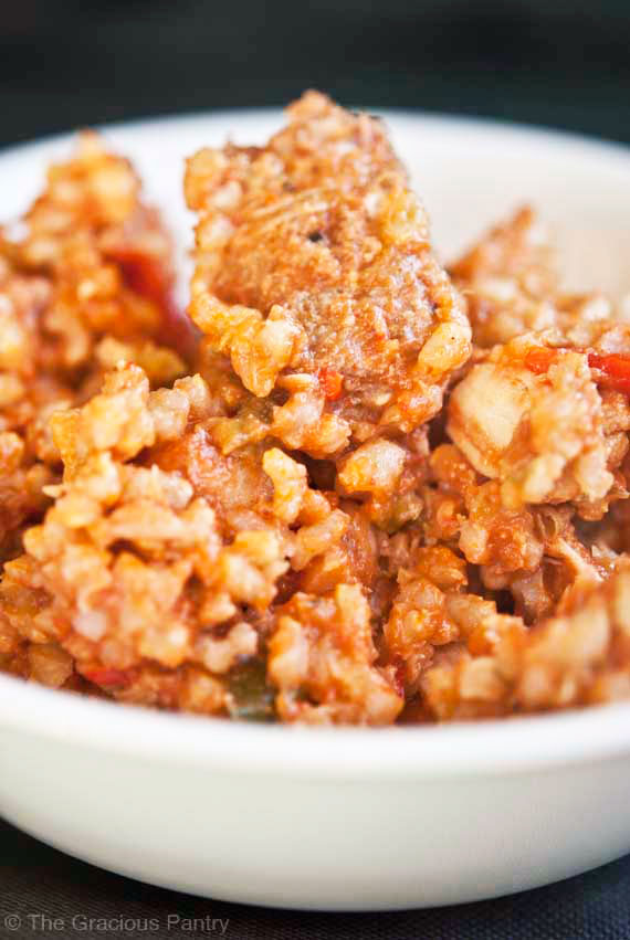 A close up shot of this Clean Eating Jambalaya in a white bowl. You see a bit of the meat and a lot of the rice.