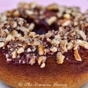 A closeup of a single donut with chopped nuts on top.