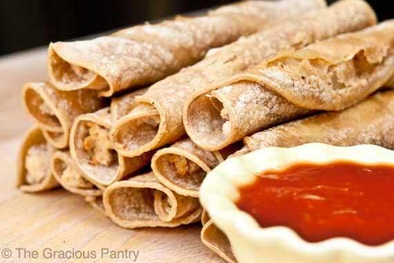 Chicken Taquitos piled up on a wood surface.