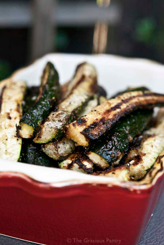 A dish filled with Grilled Zucchini on a wooden surface.