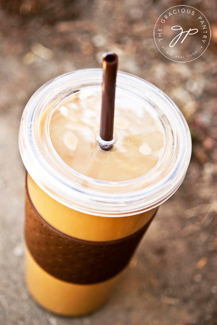 A single, clear cup with a lid and straw filled with this Clean Eating Pumpkin Spice Latte. It looks delicious and ready to drink!