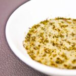 A small, white bowl sits filled with this Tarragon Dijon Dressing, ready to pour over your salad.