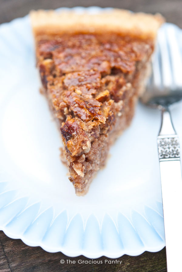 A single slice of naturally sweetened  Pecan Pie on a white plate.