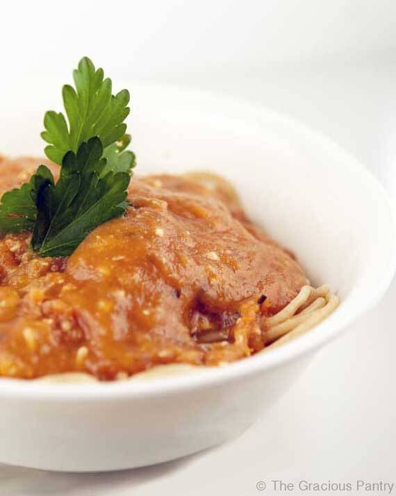 Homemade Marinara Sauce is ladled over spaghetti in a white bowl, ready to eat.