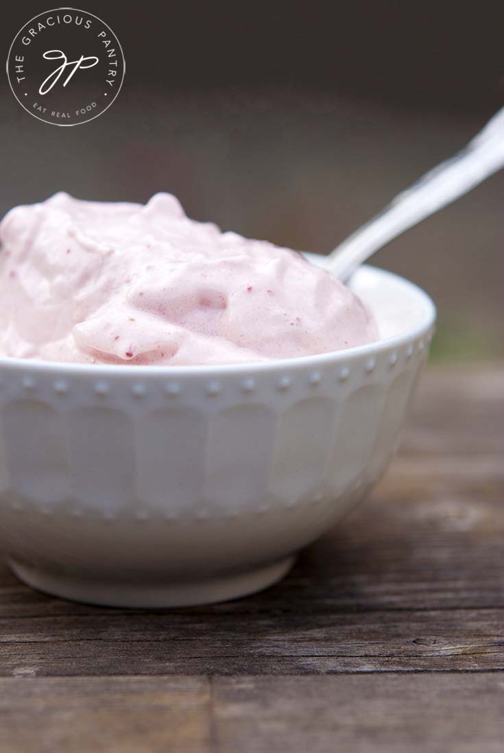 A side view of this Strawberry Banana Ice Cream Recipe in a white bowl with a spoon.