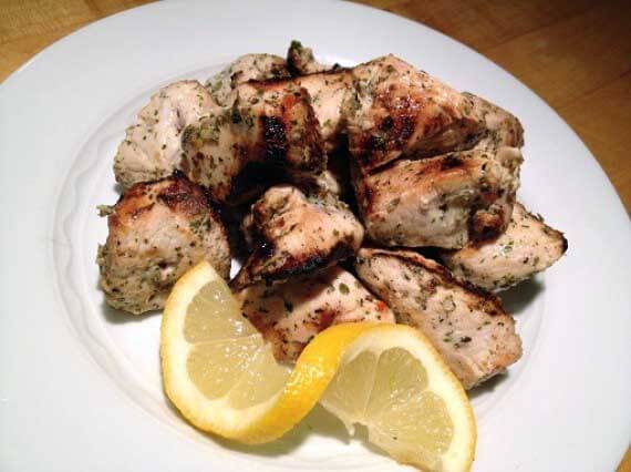 Clean eating grilled chicken souvlaki recipe served on a white plate with a twisted lemon slice.