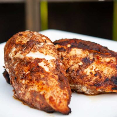Two pieces of golden-brown, grilled chicken sit seasoned, just of the grill, with this Middle Eastern Grilled Chicken Rub.