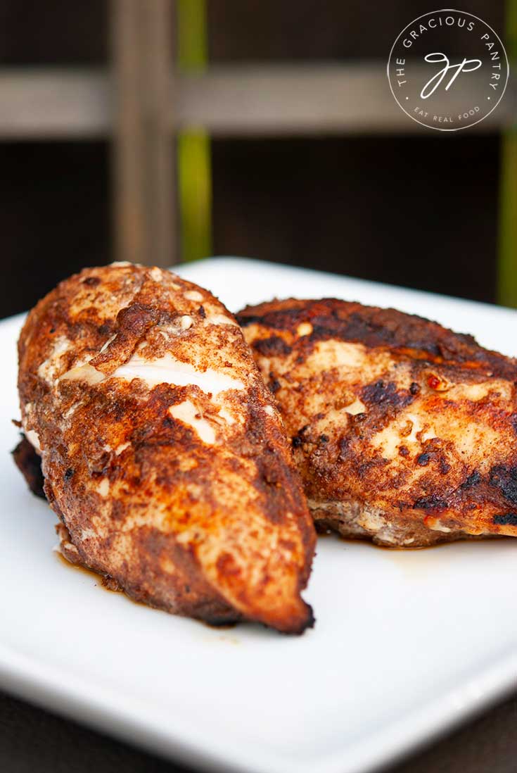 Two pieces of golden-brown, grilled chicken sit seasoned, just of the grill, with this Middle Eastern Grilled Chicken Rub.