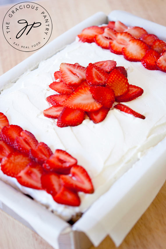 A view of this Clean Eating Canada Day Cake from the side. You can see the white frosting over the top and the bright red strawberry slices placed in the form of the Canadian flag.