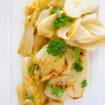 Baked fennel sits on a serving platter, fresh out of the oven.