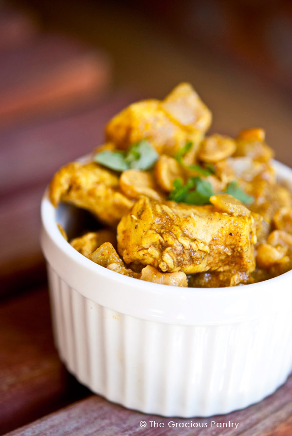 Clean Eating Chicken Korma Recipe shown up close. You see the chicken piled high in the white bowl with a golden sheen from all the aromatic herbs and spices.